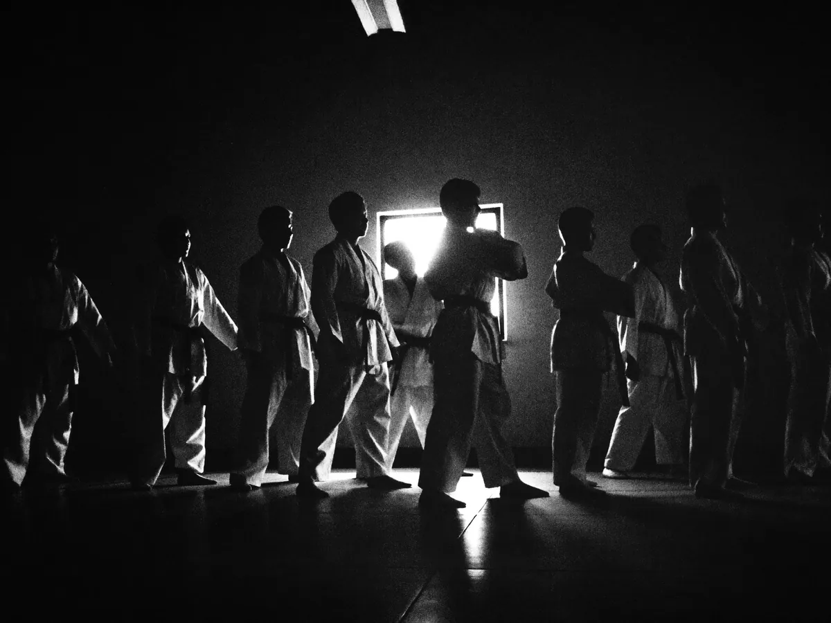 A line of students in gis silhouetted against the doorway light during class